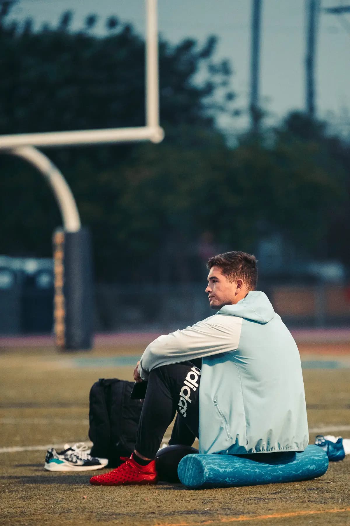 Athlete resting against the goalpost padding between takes