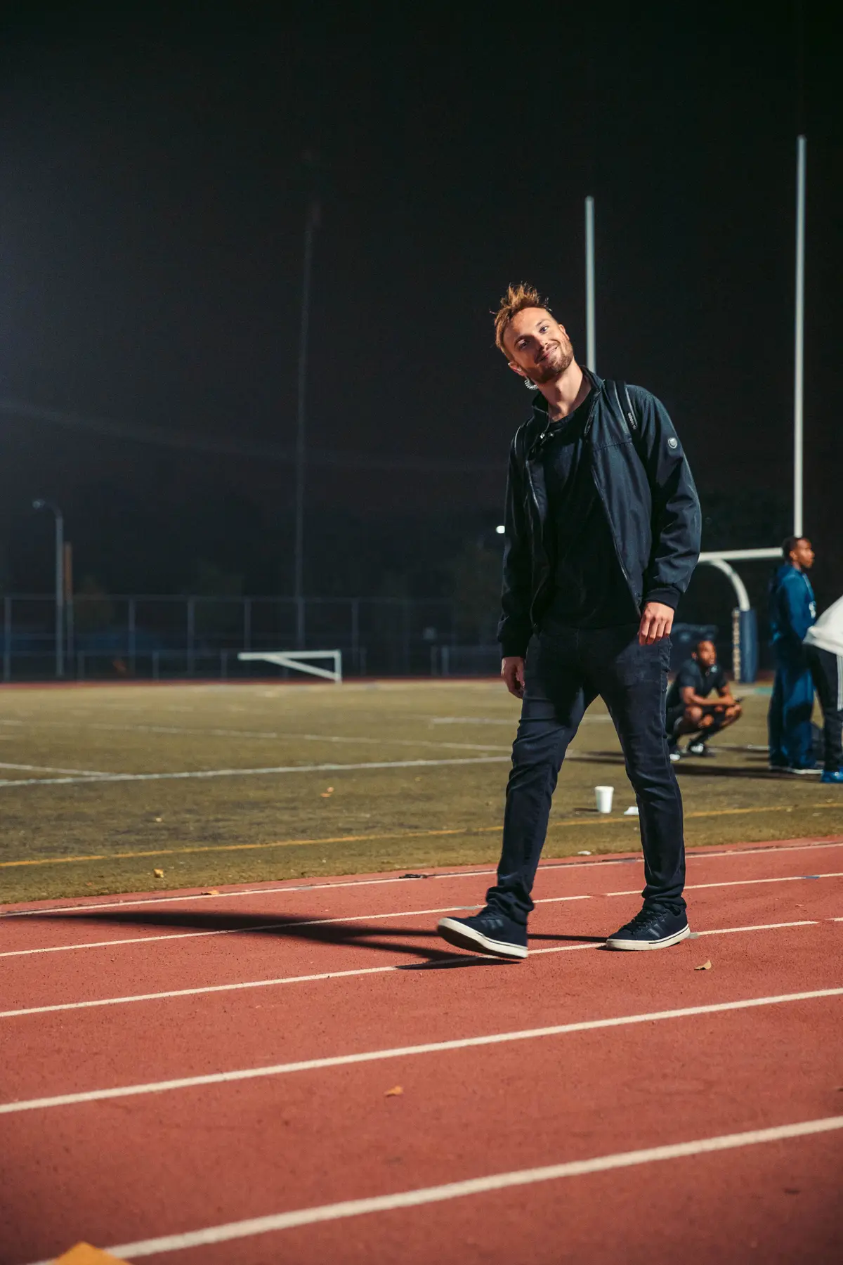 Director walking the field between setups under stadium lights