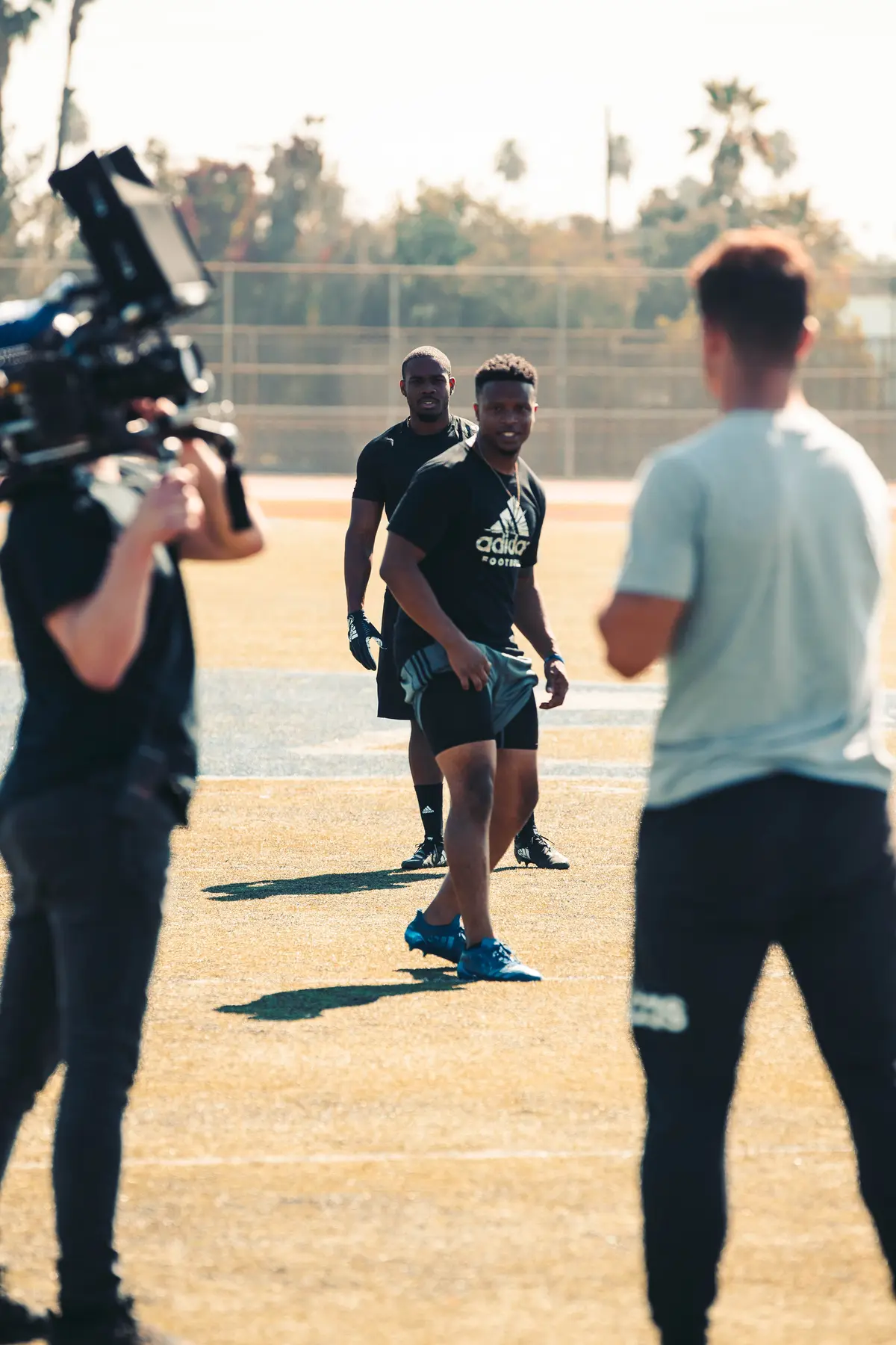 Operator filming two athletes running the play