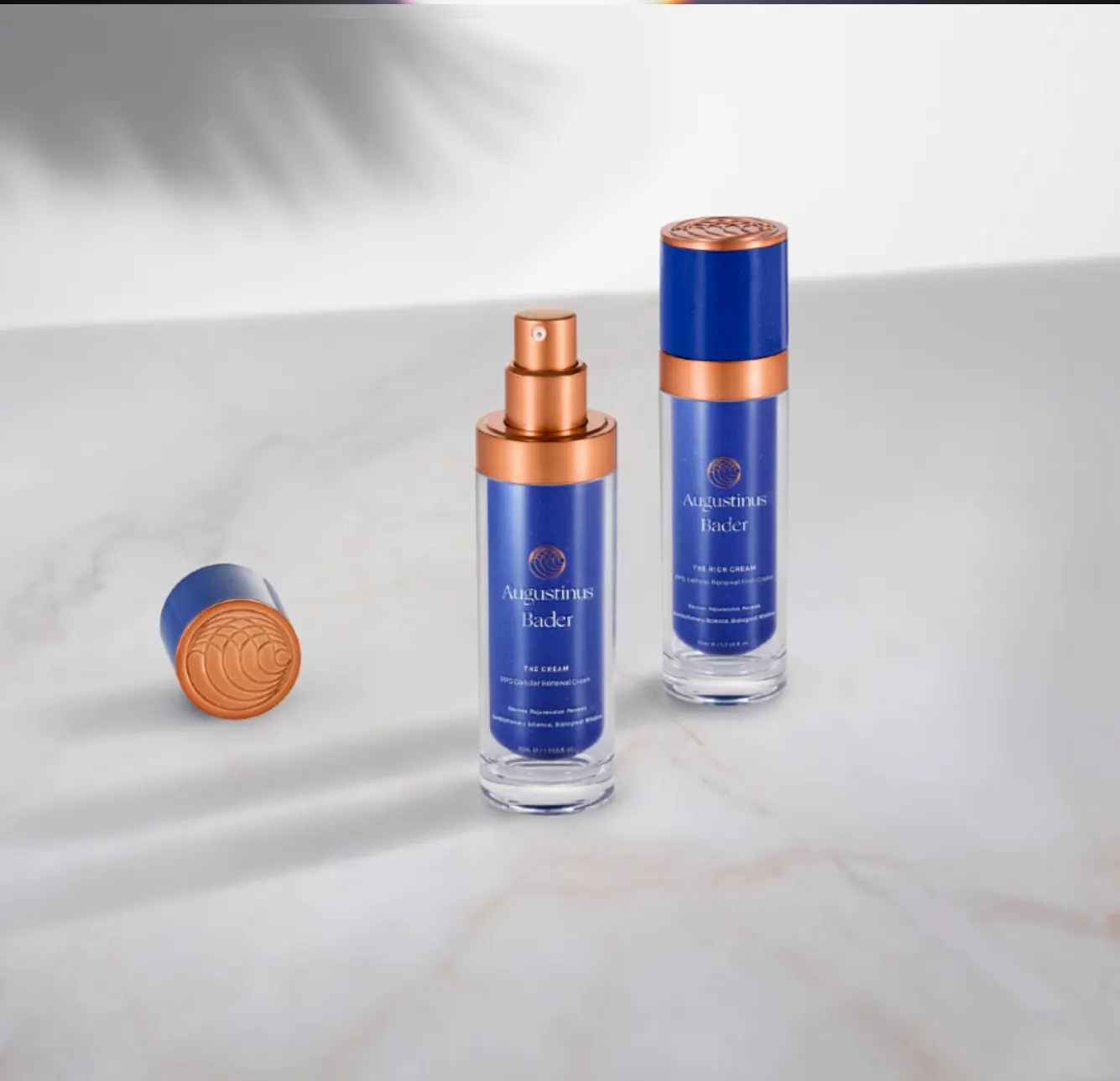 Two bottles and a loose cap on marble under palm-frond shadow